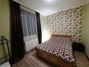 a bedroom with a bed and a large window at Kesi’s House in Borjomi