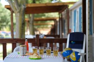 a table with glasses of beer and a plate of food at Happy Camp mobile homes in Camping Village Free Time in Marina di Bibbona