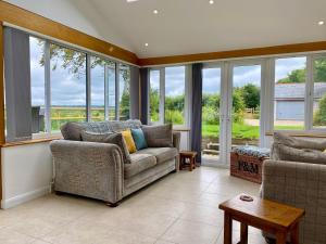 a living room with a couch and some windows at Badges Cottage for 5 Near Dartmoor Beaches and Pub in Holsworthy