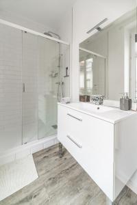 La salle de bains blanche est pourvue d'un lavabo et d'une douche. dans l'établissement Grande Maison Vichy - Maison ou Appartements en Centre ville, à Vichy
