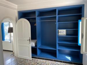 Habitación con estanterías azules y puerta blanca en Chez ADAC en Sidi Bou Saïd