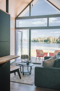 a living room with a large window and a couch at PullanHouse Līksma - small and cosy lakeside holiday house in Alūksne