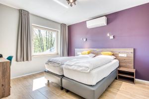 una camera con pareti viola e un grande letto di HOTEL L'AVENUE a Libramont