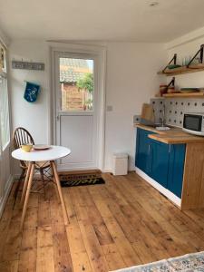 a kitchen with a table and blue cabinets and a table at Seaside 1 Bed Studio Conversion in Selsey