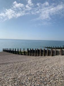 a beach with a wooden fence and the ocean at Seaside 1 Bed Studio Conversion in Selsey