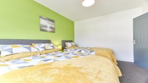 a bedroom with two beds and a green wall at Newbiggin House - Newbiggin by the Sea in Woodhorn