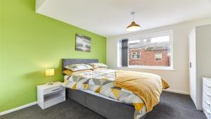 a bedroom with green walls and a bed and a window at Newbiggin House - Newbiggin by the Sea in Woodhorn