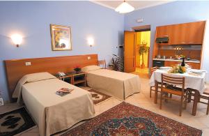 a room with two beds and a table and a kitchen at Casa Vacanze Provenzale in Torre Pellice