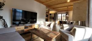 een woonkamer met een grote televisie en witte stoelen bij Hochalmbahnen Chalets Rauris 1-02, Maislaufeldweg 1b in Rauris