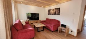 ein Wohnzimmer mit 2 roten Stühlen und einem TV in der Unterkunft Hochalmbahnen Chalets Rauris 1-18, Maislaufeldweg 1t in Rauris