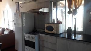 cocina con nevera blanca y microondas en casa de campo a 40 km de Rosario 