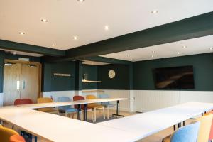 a conference room with tables and chairs and a flat screen tv at Westmorland Hotel Tebay in Tebay