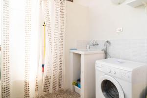 uma lavandaria com uma máquina de lavar roupa e um lavatório em Casa Venera sull'etna em Nicolosi