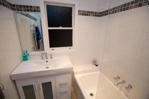 a white bathroom with a sink and a shower at Bush & Bay Cottage in Erowal Bay +28 photos