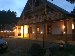 a large wooden house with a car parked in front of it at Swornegacie Villa nad Zbrzycą in Wielkie Zanie