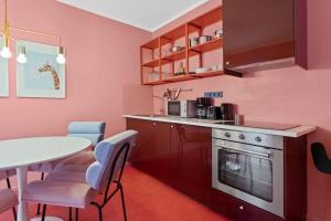 eine Küche mit rosa Wänden sowie einem Tisch und Stühlen in der Unterkunft Crazy 44sqm 3room maisonette apt Near center in Berlin