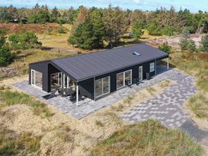 Holiday home Oksbøl LXXXIV في Oksbøl: إطلالة علوية على منزل ذو سقف شمسي