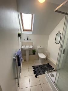 La salle de bains est pourvue d'un lavabo, de toilettes et d'une fenêtre. dans l'établissement Modern Spacious Flat In Ipswich - Sleeps 6 - Parking, à Freston