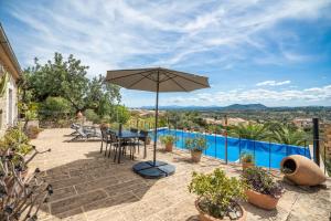 patio con tavolo, ombrellone e piscina di CAN PULIT - finca romántica para 2 con piscina y vistas en Selva Mallorca a Selva