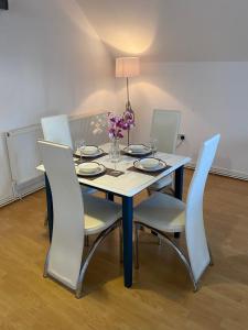 a dining room table with chairs and a vase of flowers at Modern Spacious Flat In Ipswich - Sleeps 6 - Parking in Freston