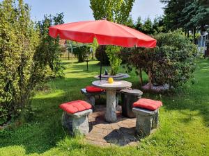 a table and four stools with a red umbrella at Ferienwohnung "Haus Sonnenblick" in Trautenstein