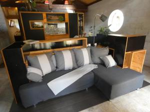 a gray couch with white pillows in a room at Gîte l'Atelier Bois in Gaillères