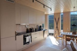 a kitchen with white cabinets and a table and a dining room at Ny leilighet på Kvitfjell Vest. Ski inn/ut in Favang