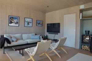 sala de estar con sofá, sillas y TV en Ny leilighet på Kvitfjell Vest. Ski inn/ut, en Favang