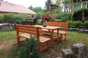 een houten tafel en twee banken in de tuin bij Ferienwohnung Lachmann in Benneckenstein