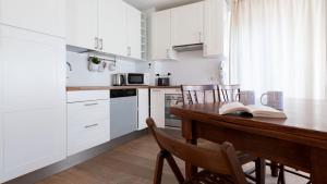 una cucina con armadi bianchi e un tavolo in legno con sedie di Italianway - Milano 35 a Bormio
