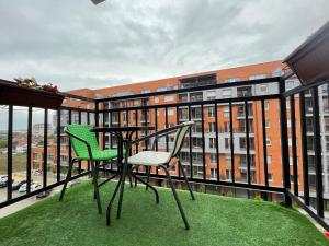 Daily Apartment Prishtina في بريشتيني: بلكونه فيها طاوله وكراسي ومبنى