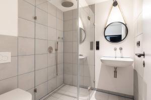 Baño blanco con lavabo y espejo en Industrial 57sqm 3room maisonette apt near center, en Berlín