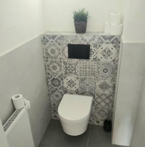 łazienka z toaletą i ścianą wyłożoną kafelkami w obiekcie Harmony Residence One WITH JACUZZI w Pradze