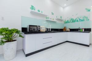 a kitchen with white cabinets and a potted plant at T-Maison Boutique Villa, with Pool, Karaoke, Billiards, near beach, Vung Tau in Vung Tau