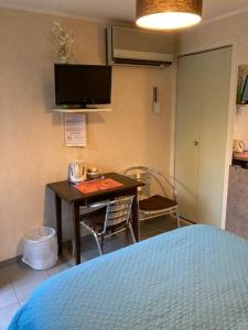 1 dormitorio con cama, mesa y TV en Logis Relais de Frejeroques, en Foissac