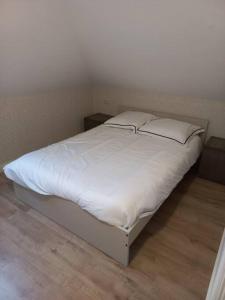 1 cama con sábanas blancas y almohadas en una habitación en Slapen in een eeuwen oude Pastorie, 