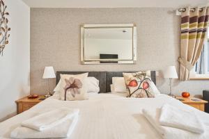 a bedroom with a white bed with pillows and a mirror at The Windmill Inn in Watchet