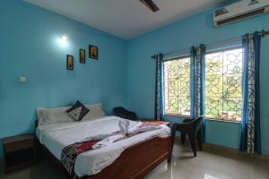 a blue bedroom with a bed and two windows at Hotel Raaj Inn in Calangute