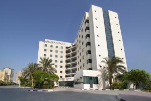 ein großes weißes Gebäude mit Palmen davor in der Unterkunft Arabian Park Dubai, an Edge by Rotana Hotel in Dubai