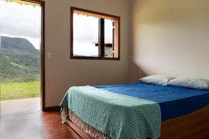 Schlafzimmer mit einem Bett mit einem Spiegel und einem Fenster in der Unterkunft Estâncias da Serra dos Alves 2 in Itabira