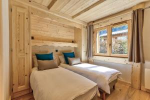 dwa łóżka w pokoju z drewnianymi ścianami w obiekcie Appartement Legno - Welkeys w Chamonix-Mont-Blanc