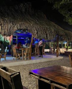 un bar con ombrellone di paglia e tavoli e sedie di PALOMINO PLAZA HOSTEL a Palomino