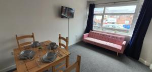 une salle à manger avec un canapé rose et une table dans l'établissement Stoke City House, à Etruria