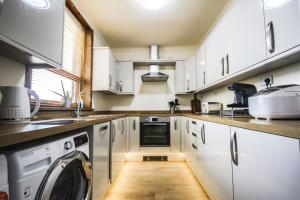 cocina con armarios blancos, lavadora y secadora en Contractors accommodation in Chorley by Lancashire Holiday Lets, en Chorley