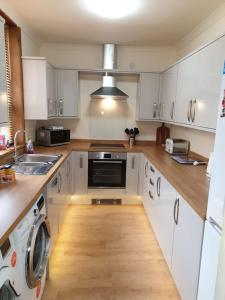 una cocina con armarios blancos y fregadero en Contractors accommodation in Chorley by Lancashire Holiday Lets en Chorley