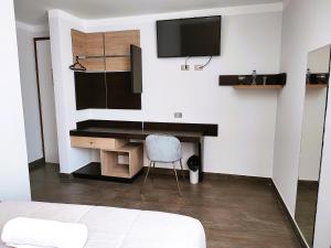 a bedroom with a desk and a tv on a wall at Tierra del Sol Centro in Moquegua