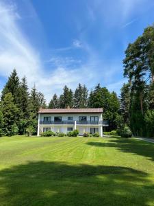 a house with a large lawn in front of it at Seeappartements Eden in Pörtschach am Wörthersee