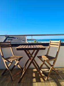 d'une table en bois et de deux chaises sur un balcon donnant sur l'océan. dans l'établissement Les Suites du Dossen, à Santec