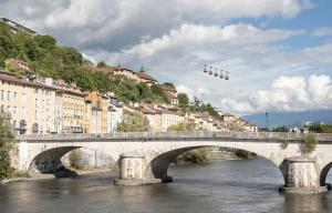 un pont sur une rivière dans une ville avec des bâtiments dans l'établissement Grenoble ~ Ecole d’architecture ~ Grand-place, à Grenoble