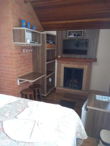 a bedroom with a fireplace and a bed and a tv at Chalé Caminho da Fonte in Monte Verde